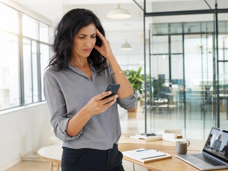 Femme agacée regardant son smartphone qui affiche une notification d'appel entrant non sollicité, illustrant le consentement obligatoire pour le SMS commercial
